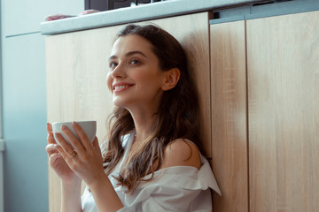 Appealing dark-eyed woman drinking coffee in the morning