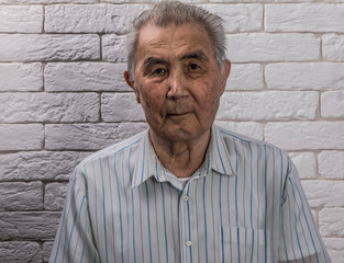 portrait of an old man, white brick wall background