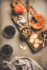 Wine and snack set. Flat-lay of two glasses of red wine, vintage corkscrews, cheese and appetizers on wooden board over grey concrete background, top view. Party food concept