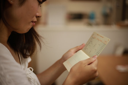 通帳を見て悩む女性