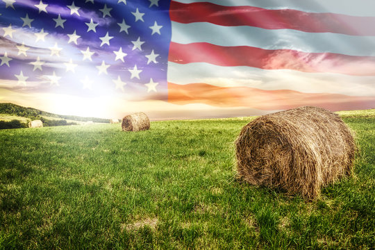 National agricultural industry concept - idyllic farm field with hay bales on on the background of the USA flag (mixed).