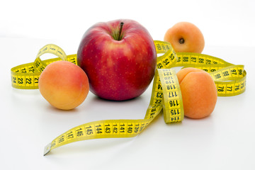 centimeter tailor and a large red apple on a completely white background. Ripe apricots.