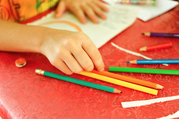 Young girl drawing with colored pencils, she is choosing a pencil in a pen holder, creativity and...