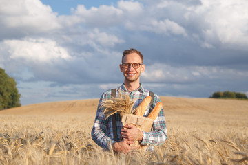 Naklejka na ściany i meble Wide smiling farmer or baker with baguettes in rye, wheat field