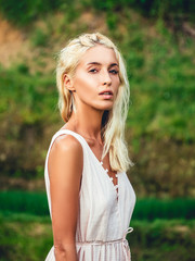 Naklejka premium Blondie girl in straw hat and white dress on the rice fields