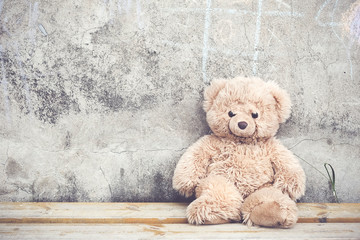 Teddy bear toy on the bench at the concrete wall with small tic tac toe game