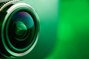 Camera lens with green backlight. Side view of the lens of camera on green background. Greencamera...