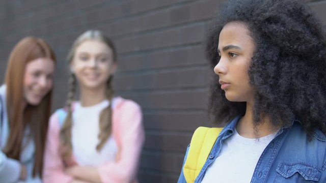 Teenagers mocking insecure biracial girl, gossiping about new classmate bullying