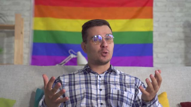 man blogger middle-aged in the shirt on the background of the flag of the LGBT records video close up