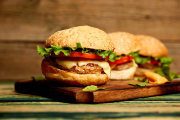 Craft beef burger  on wooden table isolated on black background..Street food, fast food. Homemade juicy burgers with cheese and  on the wooden table. Copy space.