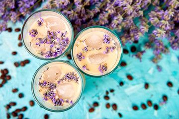 Summer drink iced coffee with lavender in glass and coffee beans on blue background. Good Morning...