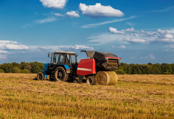 Obraz premium Straw harvesting with the help of a rotary roll forming machine in the unit with a tractor