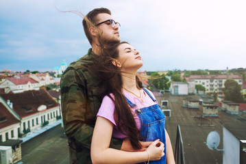 Loving couple dating on the roof. Couple in love hugging on roof with view of evening city at background