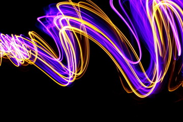 Long exposure photograph of neon purple and metallic gold colour in an abstract swirl pattern...