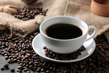 Roasted coffee grains and a cup of coffee on a brown wooden background. Robusta, Arabica.