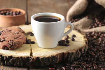 Roasted coffee grains and a cup of coffee and cookies on a brown wooden background. Robusta, Arabica.