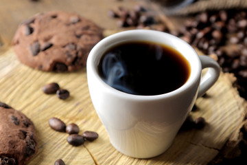 Roasted coffee grains and a cup of coffee on a brown wooden background. Robusta, Arabica.