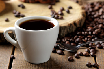 Roasted coffee grains and a cup of coffee on a brown wooden background. Robusta, Arabica.