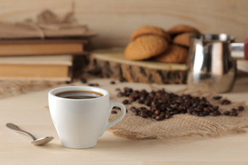 Coffee in a white cup and roasted coffee grains on a natural wooden table. Robusta, Arabica