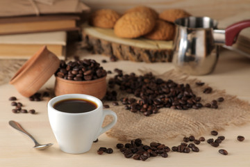 Coffee in a white cup and roasted coffee grains on a natural wooden table. Robusta, Arabica