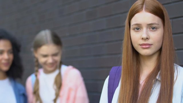 Teen classmates laughing at ginger girl, spreading malicious rumors, bullying