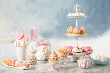 Fototapeta na wymiar Candy bar with different sweets on white marble table against color background