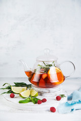 Summer tea in a kettle of fresh fruit and berries. Natural berry tea light background.