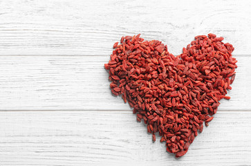 Obraz na płótnie Canvas Heart made of dried goji berries on white wooden table, top view with space for text. Healthy superfood