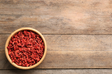 Obraz na płótnie Canvas Bowl of dried goji berries on wooden table, top view with space for text. Healthy superfood