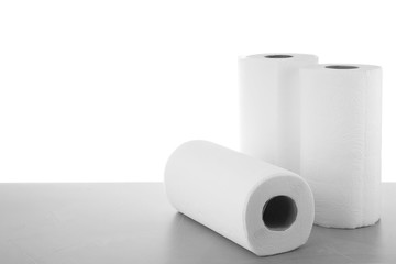 Rolls of paper towels on grey stone table against white background, space for text