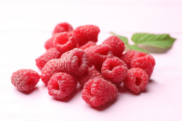 Delicious fresh ripe raspberries on pink wooden table, closeup view