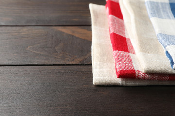 Fototapeta na wymiar Different checkered kitchen towels on wooden table, space for text