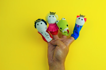 male hand wearing 4  finger puppets - king,prince,princess and dragon