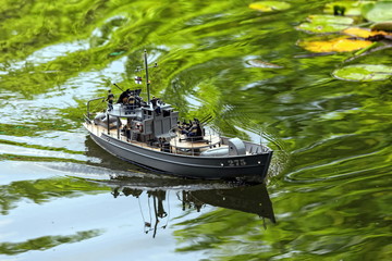 a miniature military speedboat on a pond