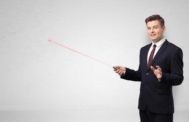Young businessman with laser pointer and copyspace white wall