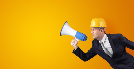 Young architect constructor yelling with megaphone and copyspace