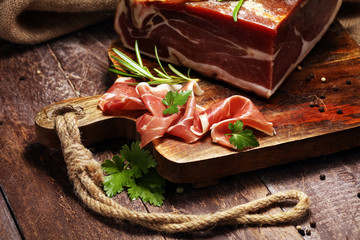 Italian prosciutto crudo or jamon with rosemary. Raw ham on wooden board