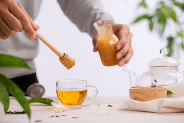 Cropped image of arista pouring honey into cup of tea