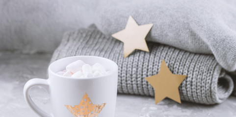 Fototapeta na wymiar cosy still life with cup with marshmallows and knitted sweaters and paper golden stars