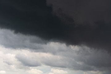 A stormy dark sky with white in the bottom, gray in the middle and black clouds on the top of the...