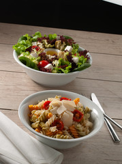 dos ensaladas sobre madera de roble una de verduras  y otra de pasta. two salads on oak wood, one with vegetables and the other with pasta.