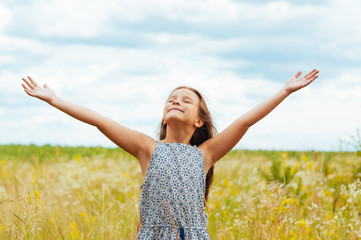 Naklejka na ściany i meble Emotional portrait of a little girl in the field enjoying the summer