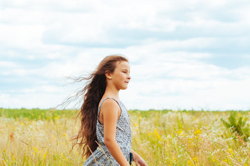 Naklejka na ściany i meble Emotional portrait of a little girl in the field enjoying the summer