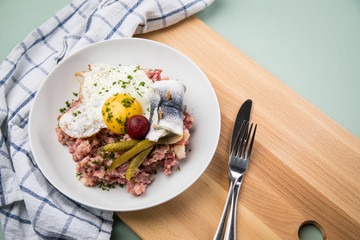 Norddeutscher Hamburger Labskaus mit Rindfleisch Corned Beef, Rote Beete, Kartoffeln, Saure Gurken, Spiegelei und Rollmops auf Teller