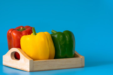 Summer of sweet bell pepper in wood box on blue background.