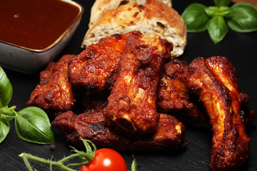 Spicy hot grilled spare ribs from a summer BBQ served with fresh tomatoes on an vintage cutting board