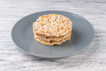 Three dried corn tortillas on a gray plate, on a white wooden table
