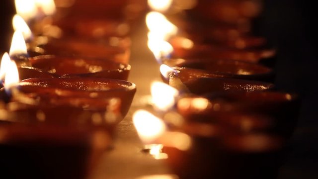 multiple oil lamps being lit in festival, happy diwali