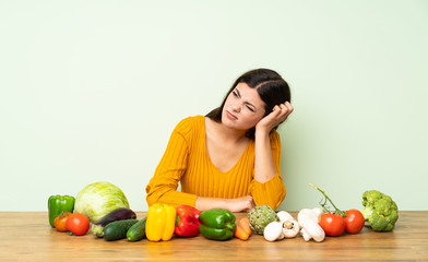 Fototapeta premium Teenager girl with many vegetables having doubts