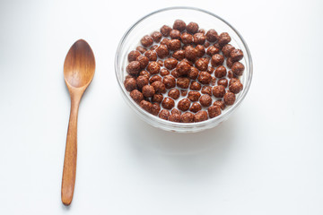 breakfast cereal with milk in a glass bowl with wooden spoon isolated on white background